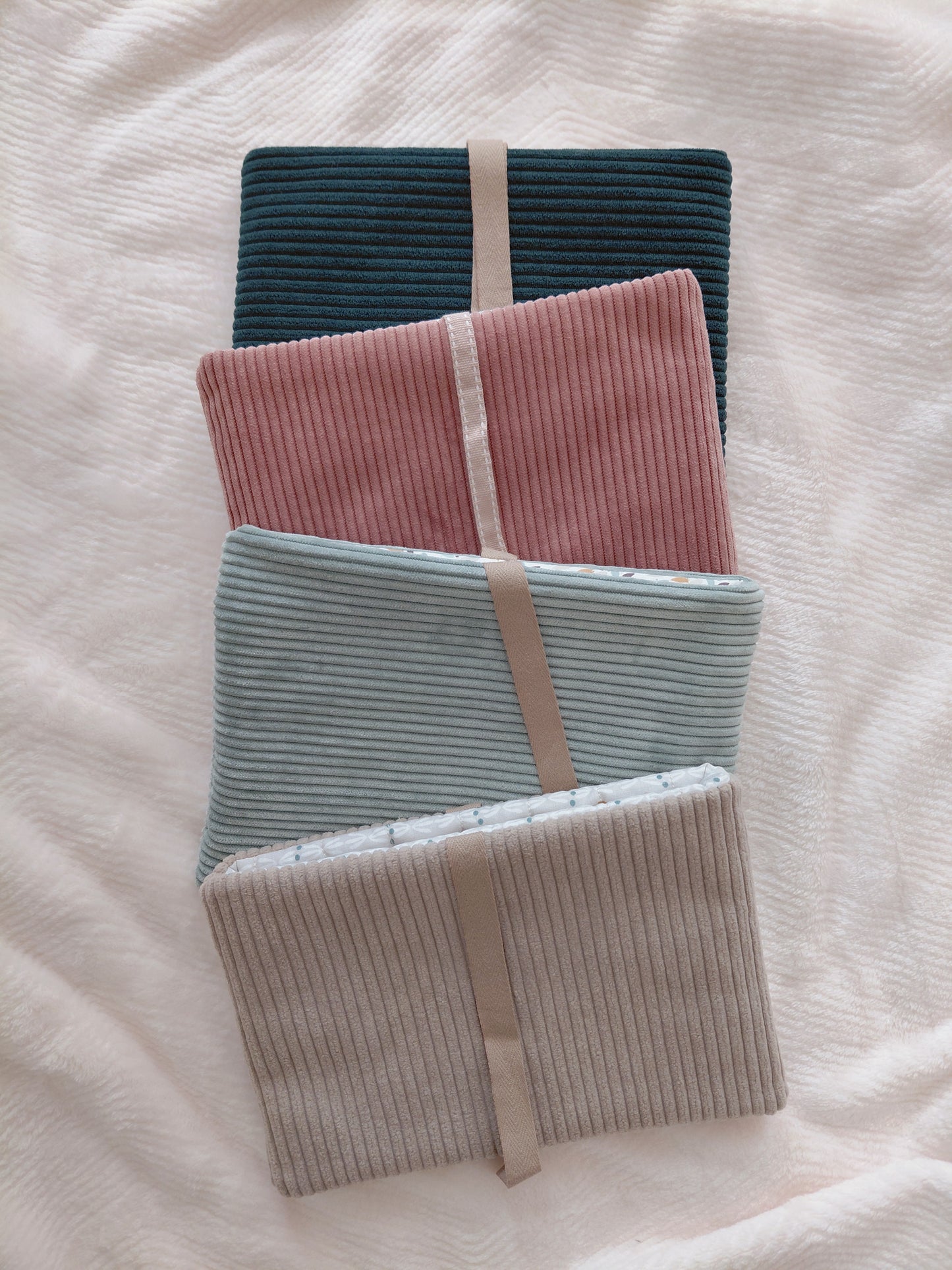 Photo de quatre pochette à livre de couleurs différentes pour présenter le nouveau concept de pochette surprise qui consiste à choisir la couleur du velours extérieur et je m'occupe de choisir le tissu intérieur assorti au tissu extérieur.