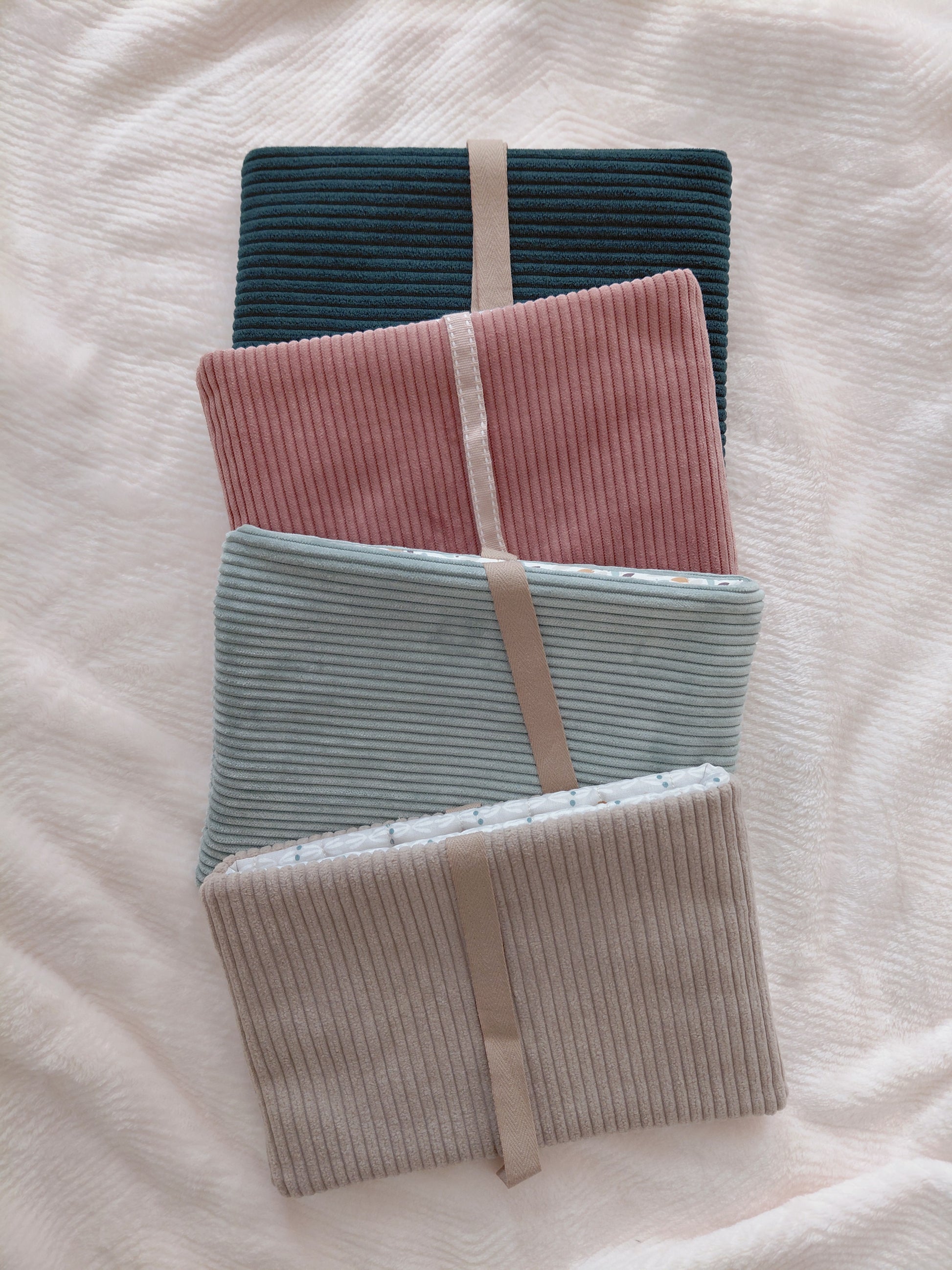 Photo de quatre pochette à livre de couleurs différentes pour présenter le nouveau concept de pochette surprise qui consiste à choisir la couleur du velours extérieur et je m'occupe de choisir le tissu intérieur assorti au tissu extérieur.