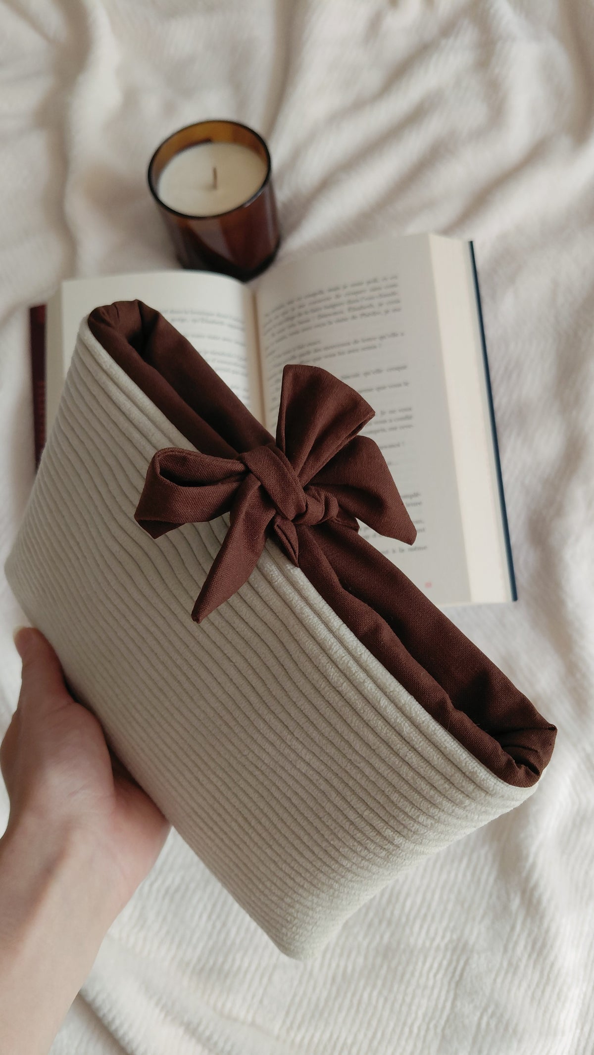 Pochette à livre format poche de la collection automne. Exterieur en velours côtelé écru et intérieur en coton couleur chocolat. Molletonnée, elle est parfaite pour emmener ses lectures partout avec soi sans les abîmer. 