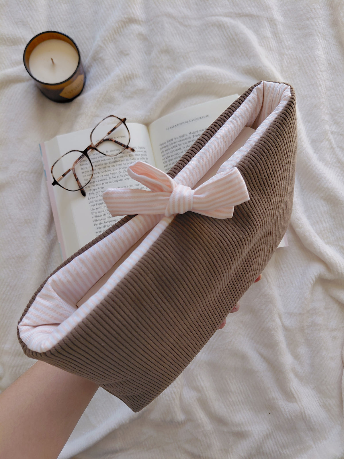 Pochette à livre en velours marron et intérieur en coton à rayures blanc et pêche. Rembourée, elle permet de transporter ses livres au quotidien