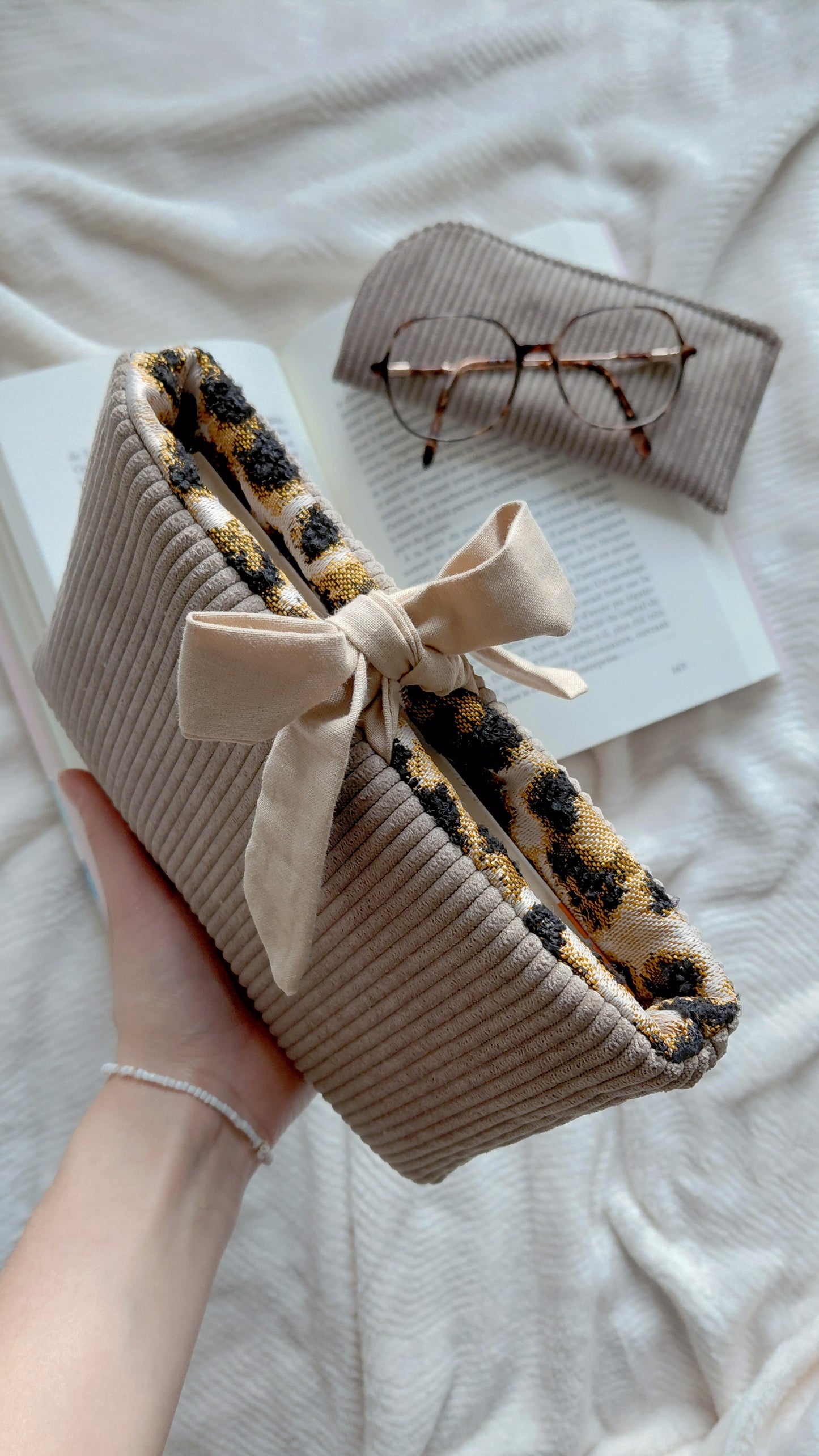 Pochette à livre en velours de couleur taupe et intérieur en coton à motifs léopard. Galon permettant de maintenir ses lectures à l'intérieur 